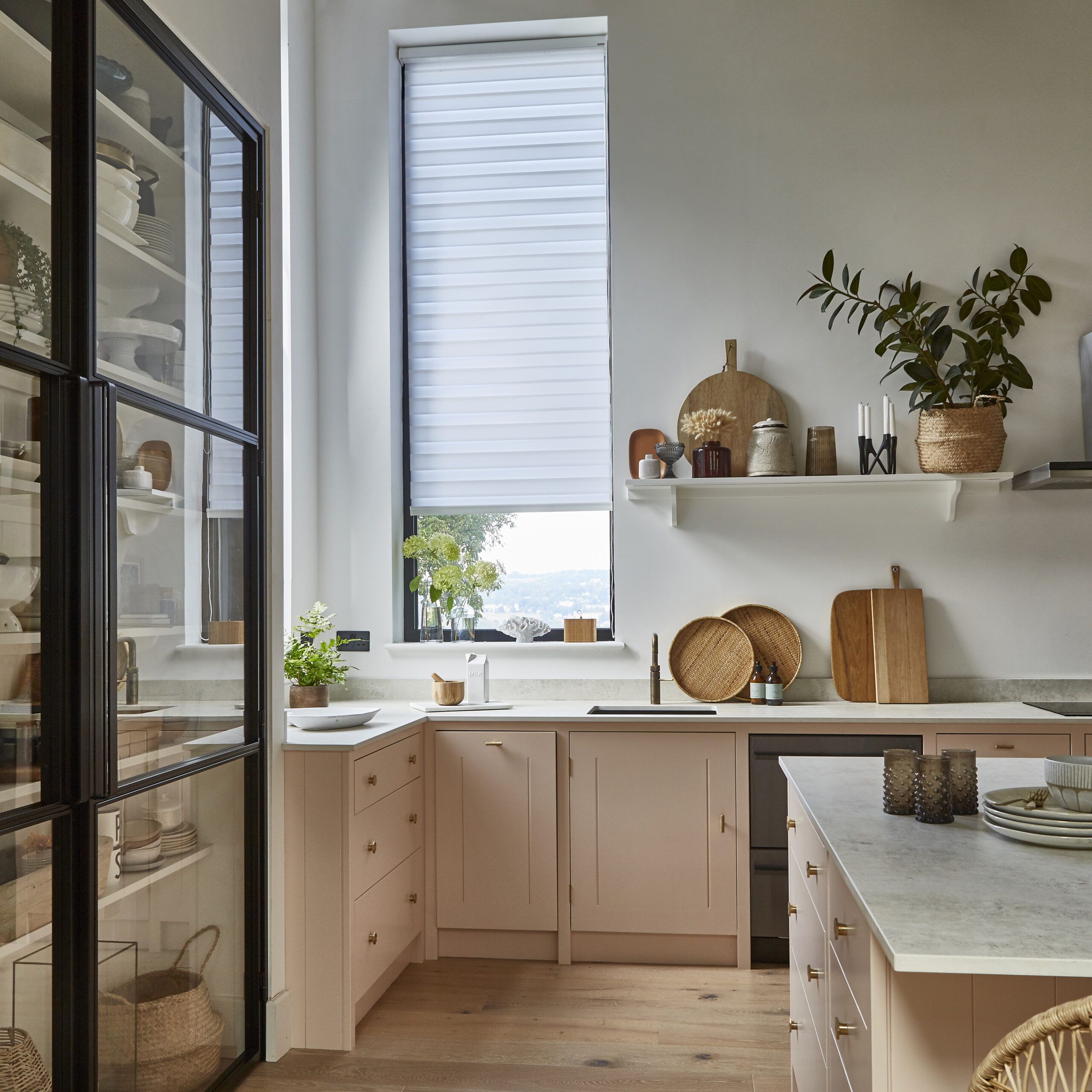 A scandanavian styled kitchen space with a elongated window fitted with a day and night blind, filtering the intensity of light. 