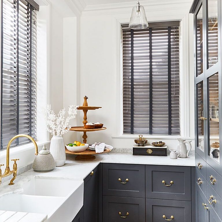 Image of blinds styled by SW Design Group. Dark cabinets in a kitchen space in constrast to white surfaces.
